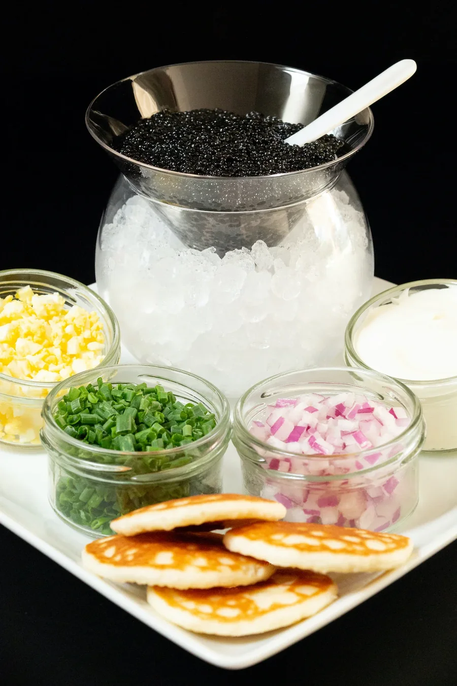 Caviar on ice with blinis, chopped egg, chives and cream